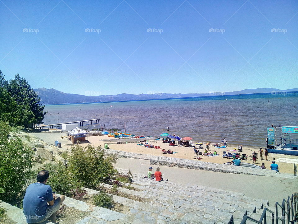 A Crowded Beach, Filled with People Enjoying the sun and the beautiful view Of the South Lake Tahoe Beach.