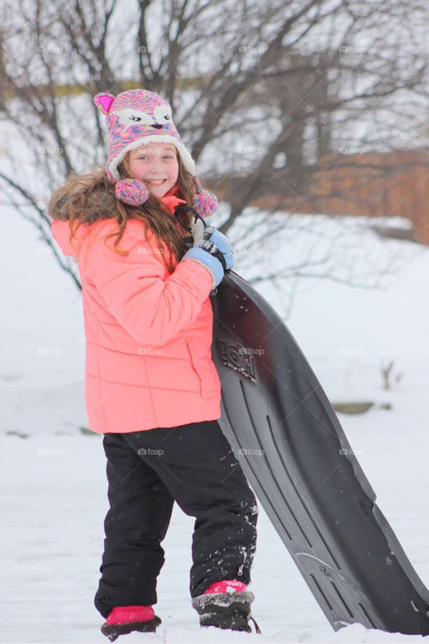 Girl holding sled during winter