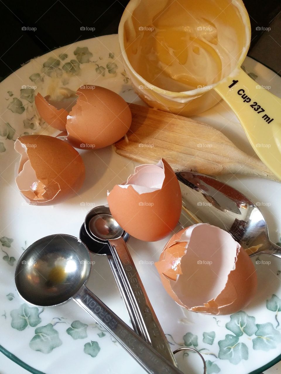 Cracked brown eggs measuring spoons and cup