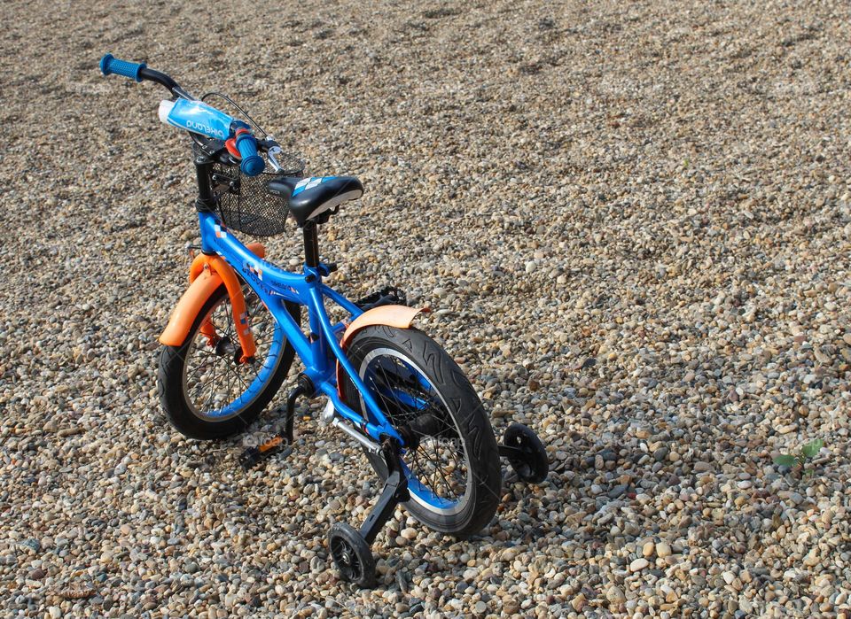 Top view of a one  blue-orange lonely children's bicycle on the gravel