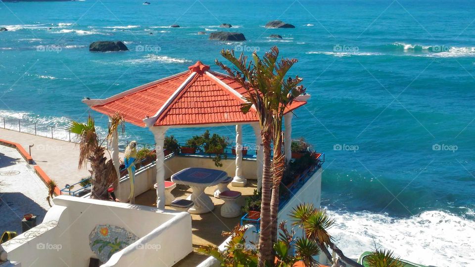 A brick and tile-roofed gazebo guarded by palms in Citara beach on the Italian island of Ischia