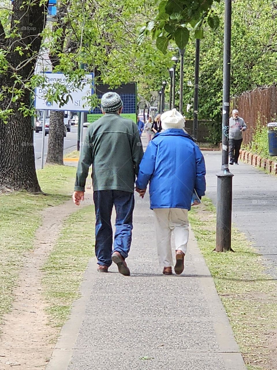 The cute elderly couple hold hands as they walk together. They love each other, and they give each other support. A sweet, lovable, tender gesture that lasts through their relationship.