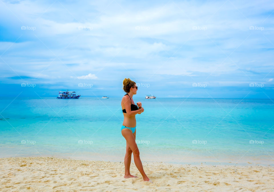 Young female person in bikini enjoying summer vacation time on tropical sandy beach 