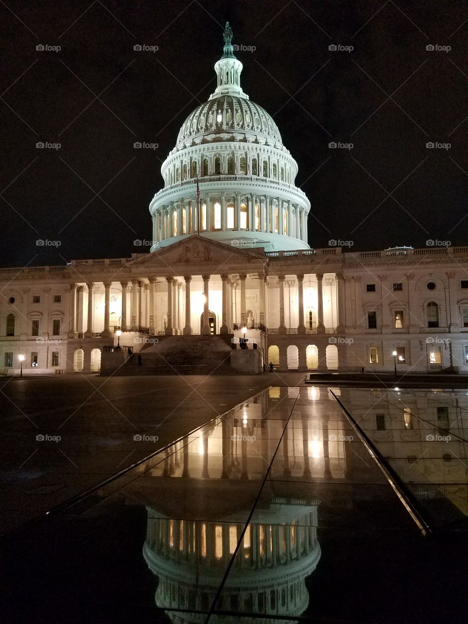 Capitol Building at night with reflection of the dome in a puddle of water. Washington, DC