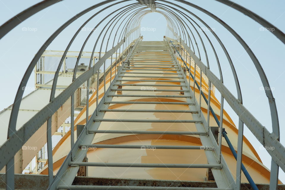 grey metal staircase with railing leading up to the big yellow tower
