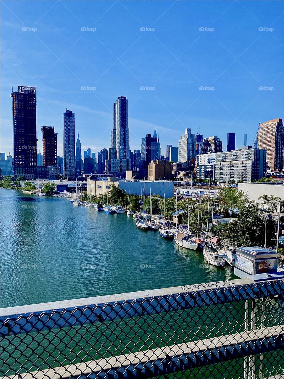 This is an absolutely spectacular view of NYC from the „Pulaski Bridge“ at „Newtown Creek“ in LIC, Queens. Behind the LIC skyscrapers „Manhattan“ is visible on a clear bright and sunny day as this is. 2023. Hypnotic Productions