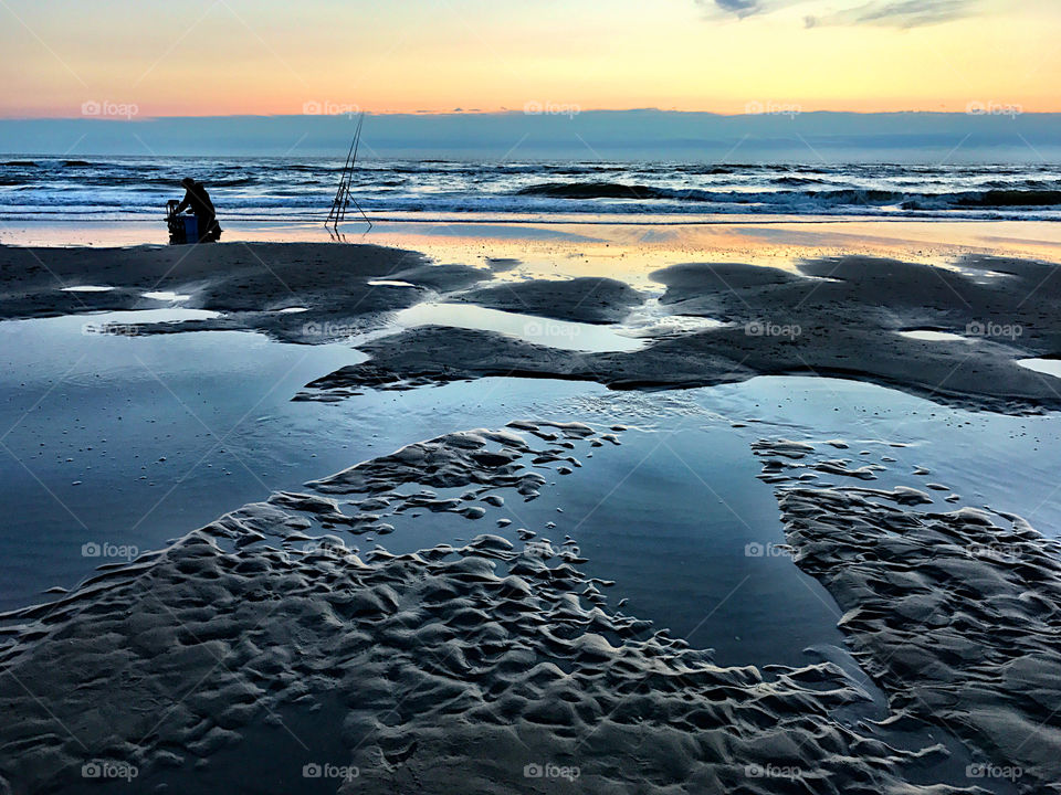 Lonely fisherman packs his things after sunset 