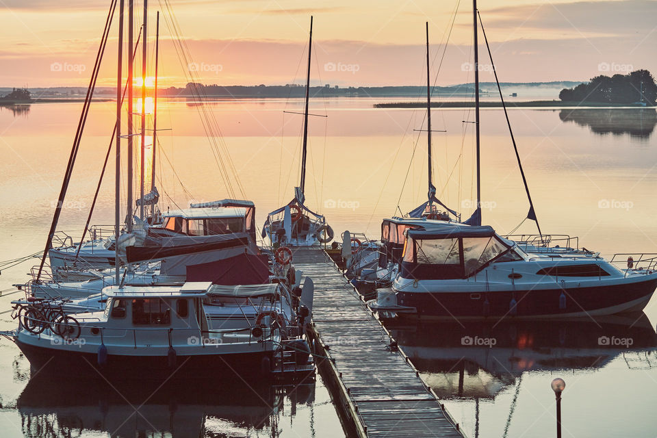 Yachts and boats moored in a harbour at sunrise. Candid people, real moments, authentic situations