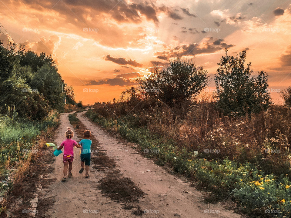 Children walk along the road to sunset