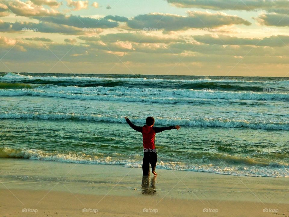 Rear view of boy enjoying at beach