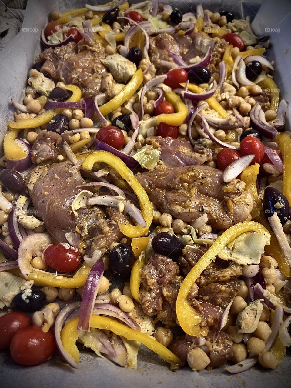 Mediterranean chicken, before cooked.  Klamata olives yellow pepper purple onion grape tomato chicken thighs chick peas 