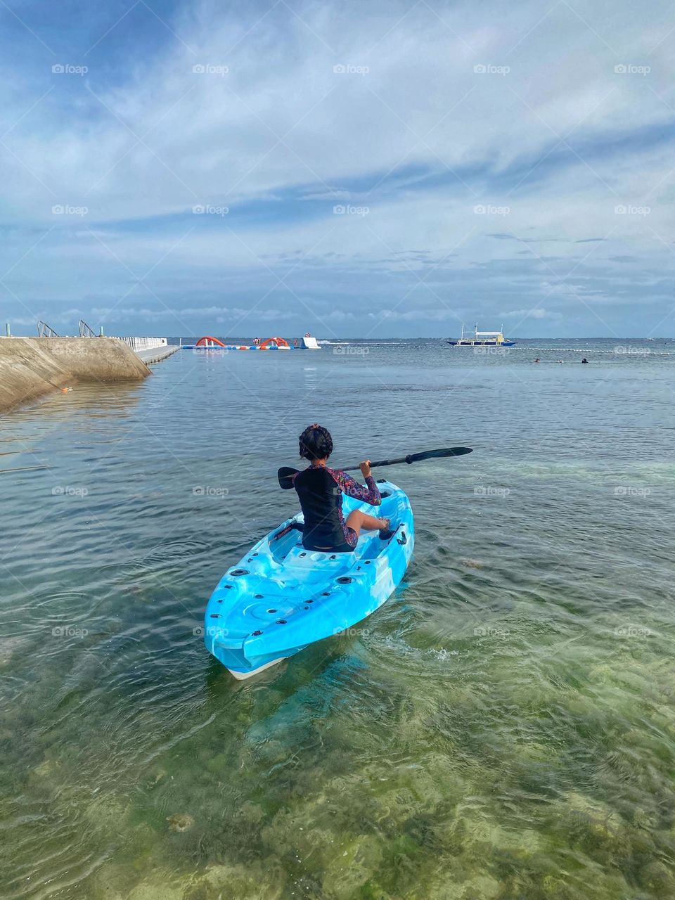 A woman enjoys quality time in her kayak. Calm tropical beach at Mactan Cebu Philippines. 