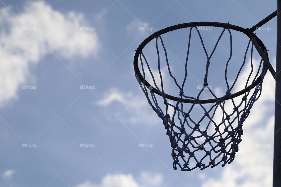 Basketball hoop with clear sky with some clouds as background 