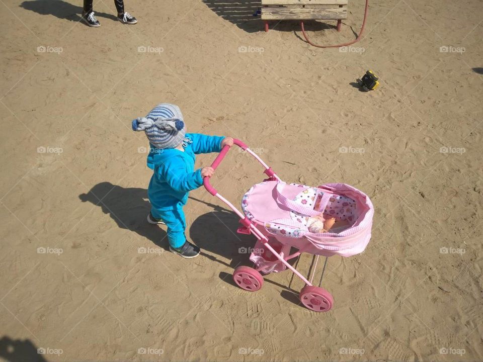 Little girl, child, carries a pink stroller