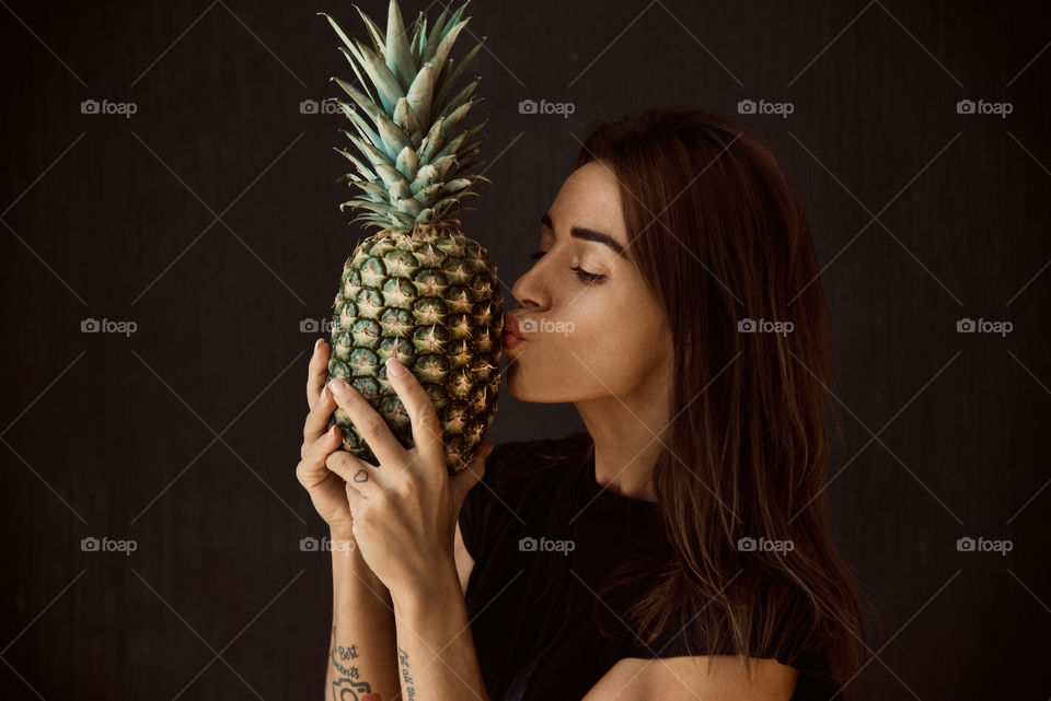 beautiful girl posing on camera with pineapple in her hands