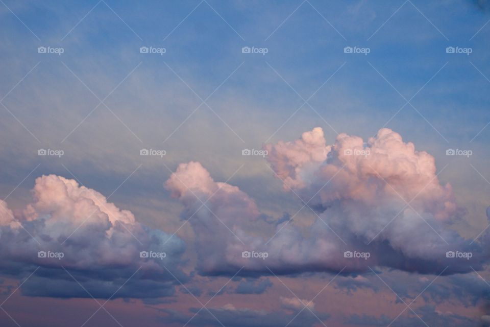 Pastel-colored clouds, partially illuminated at the tops, by low-angled sunlight