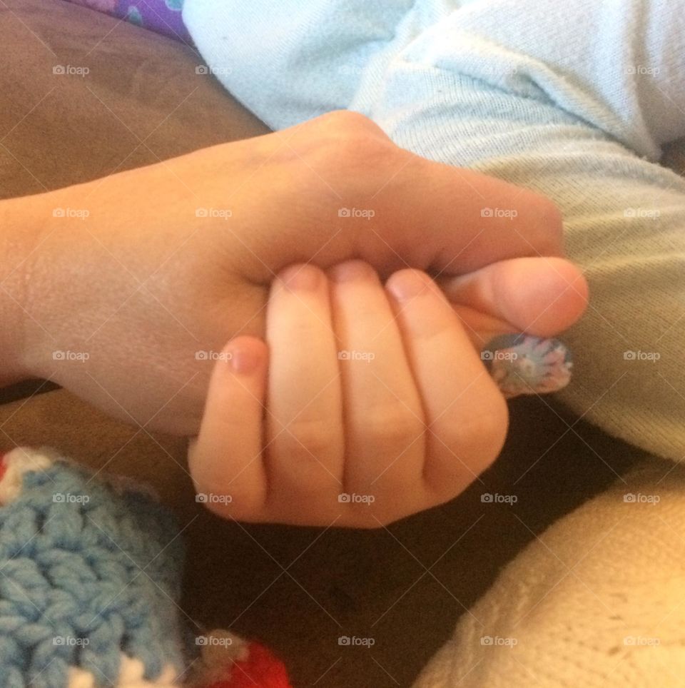 Grandma and grand daughter holding hands, while napping on the couch
