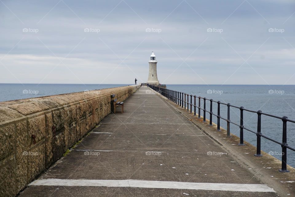 Triangular Landscape formed by a wall in one side and a metal barrier in the other with the lighthouse being a central point …