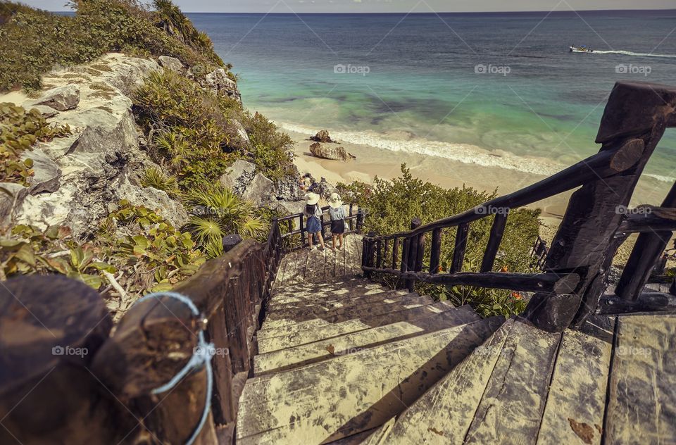 Wooden staircase descends towards Tulum beach in Mexico to allow tourists to overcome the difference in height to get to the beach.