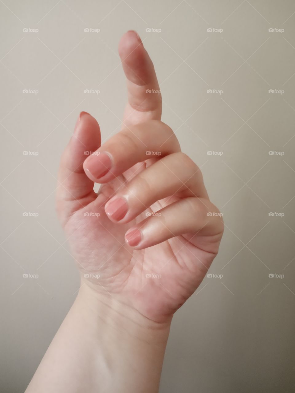 Manicured nails, painted with glossy nude nail polish.