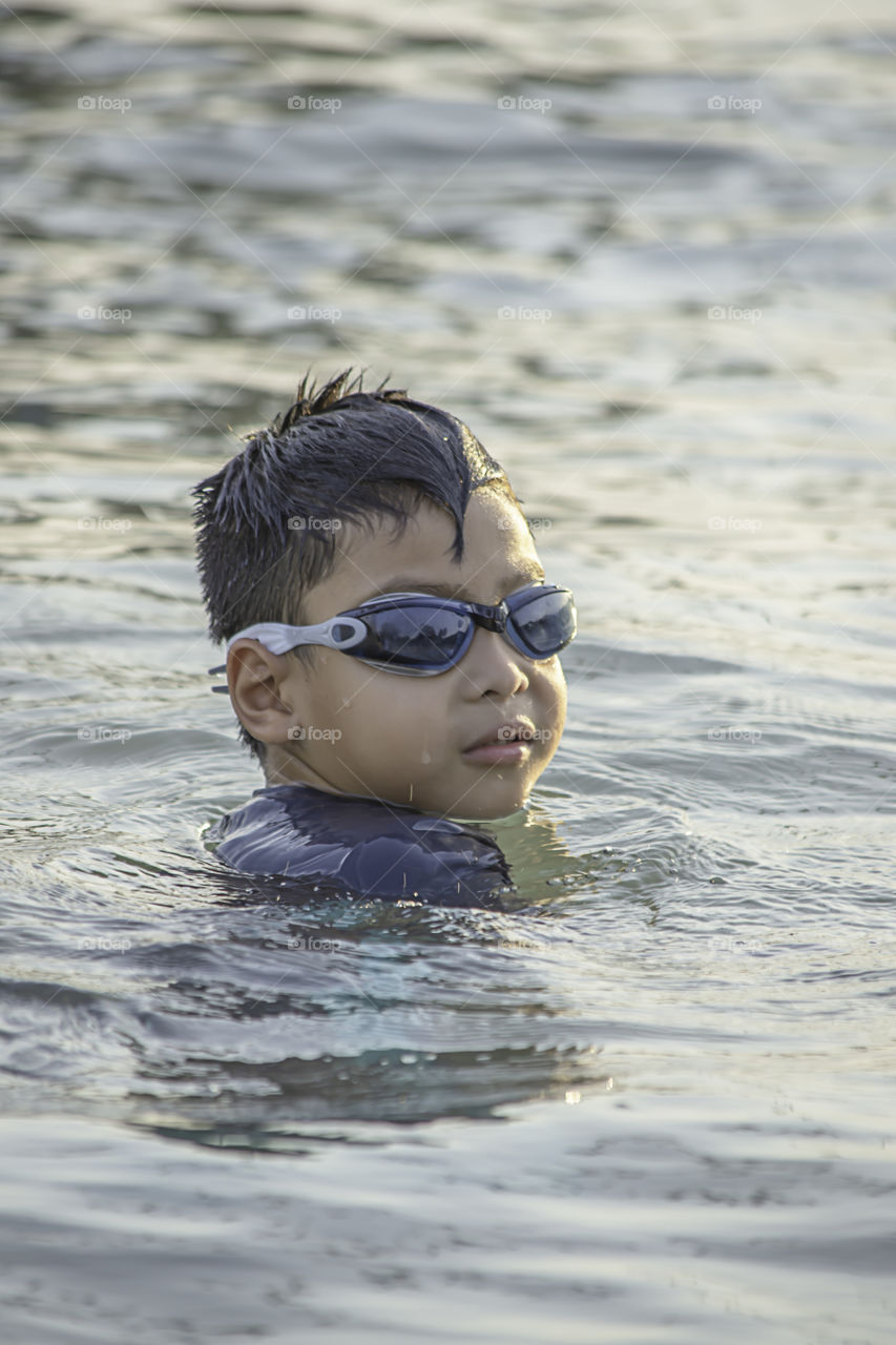 Asian boy wearing swimming goggles In the sea