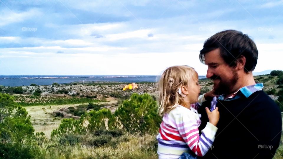 Father and daughter standing on the garrigue in Fitou, France with wiew over Chateau Fitou.