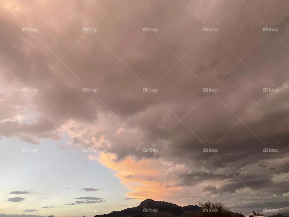 A mountain with the colorful background of pink and grey clouds. 