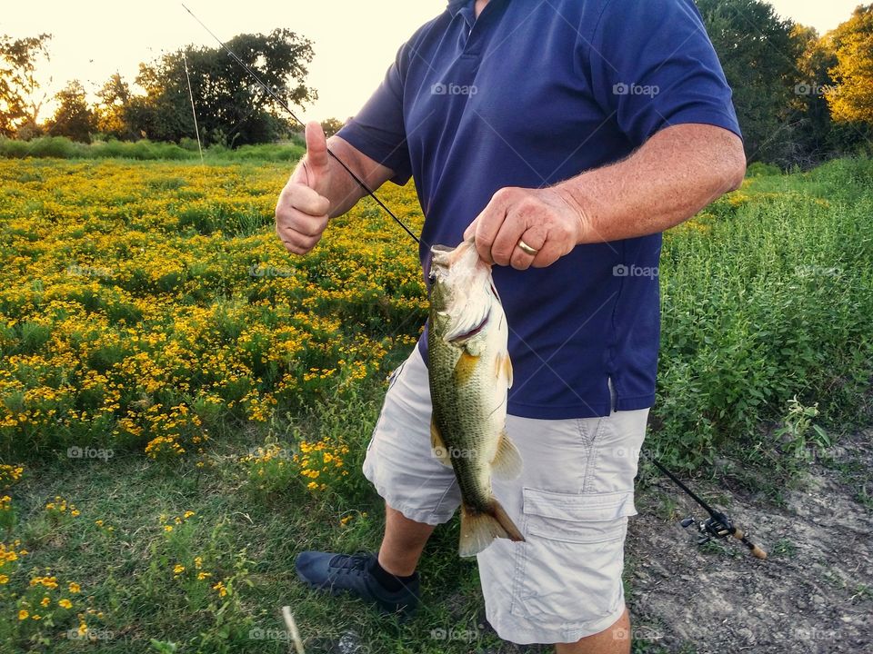 A man Catching Bass on a warm summers evening with a big thumbs up It's Summertime!