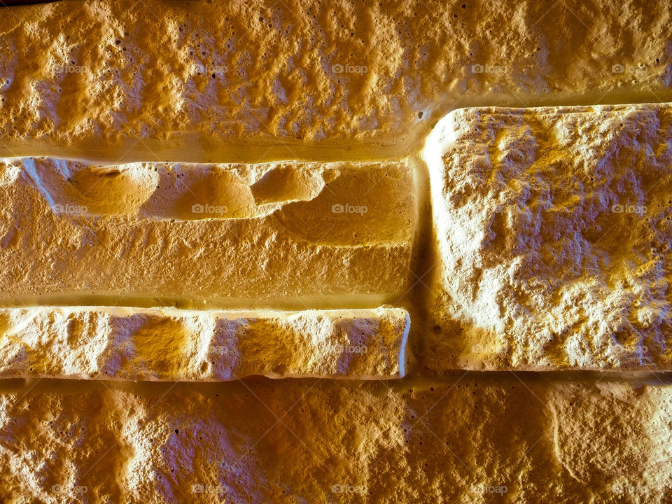 Wall of light decorative stone under the rock with protrusions and shadows