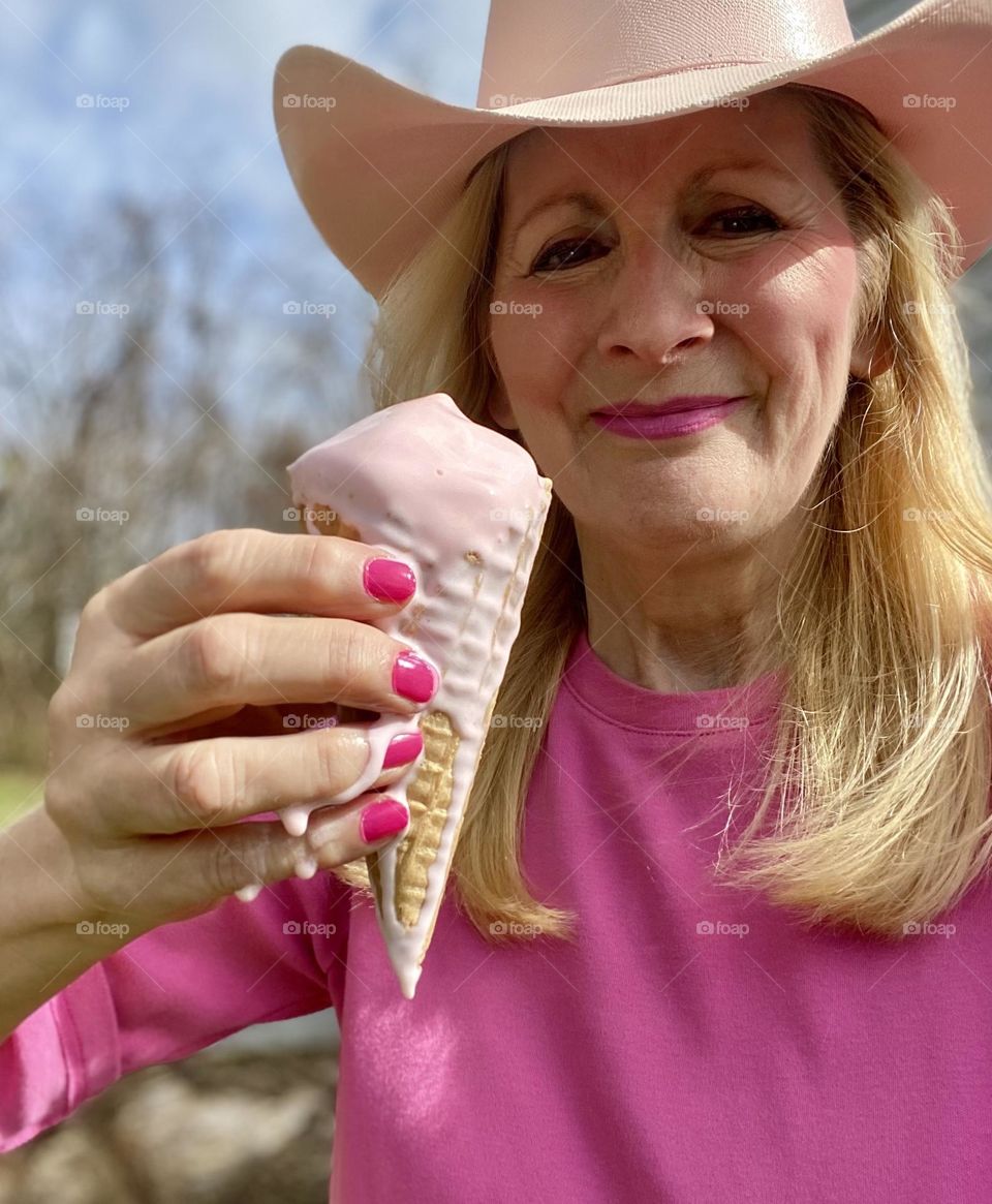 Woman in cowboy hat holding a strawberry waffle cone