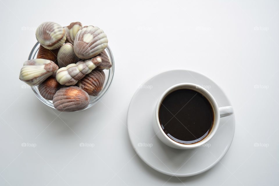 cup of coffee with chocolate candies on a white background