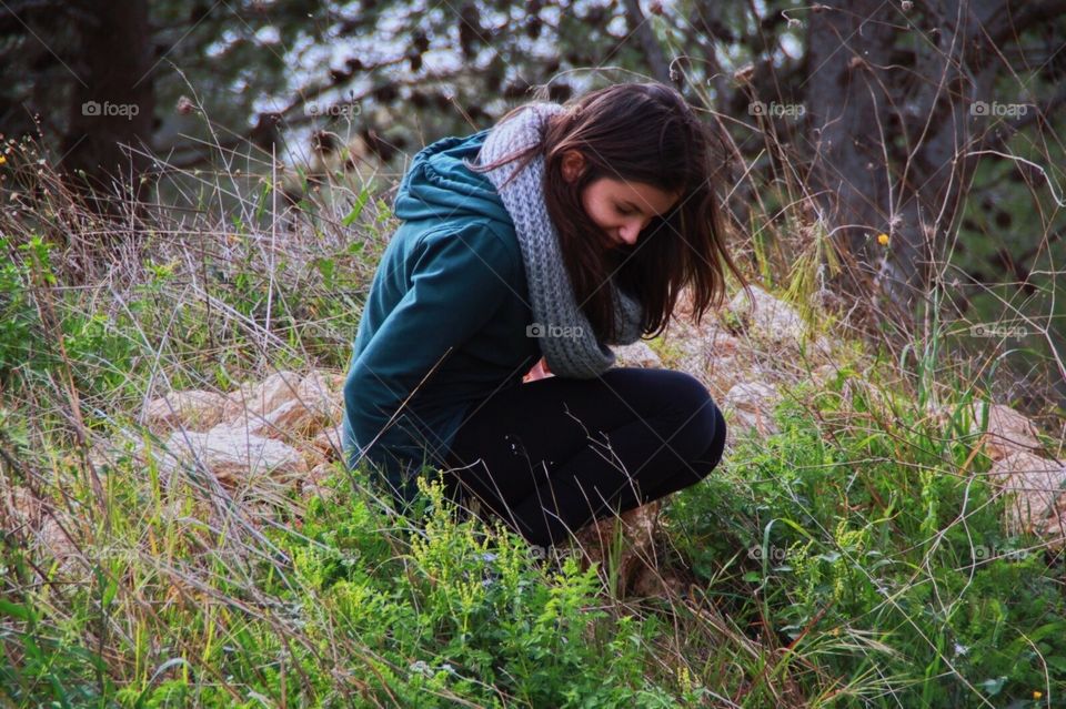 Portrait of a girl dressed in green wearing scarf in the wilderness, rocks, brown haired.