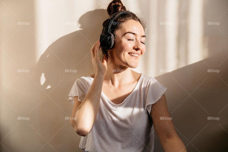 Young millennial woman listening to music at home, being happy.