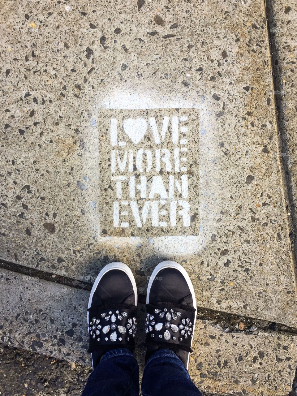 Graffiti in city. Looking down to stylish woman shoes. Love Inscription. Love more than ever.