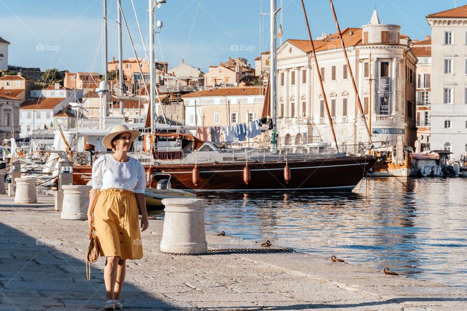 Young woman wearing summer clothes and sunhat exploring the beautiful town of Piran in Slovenia during summer