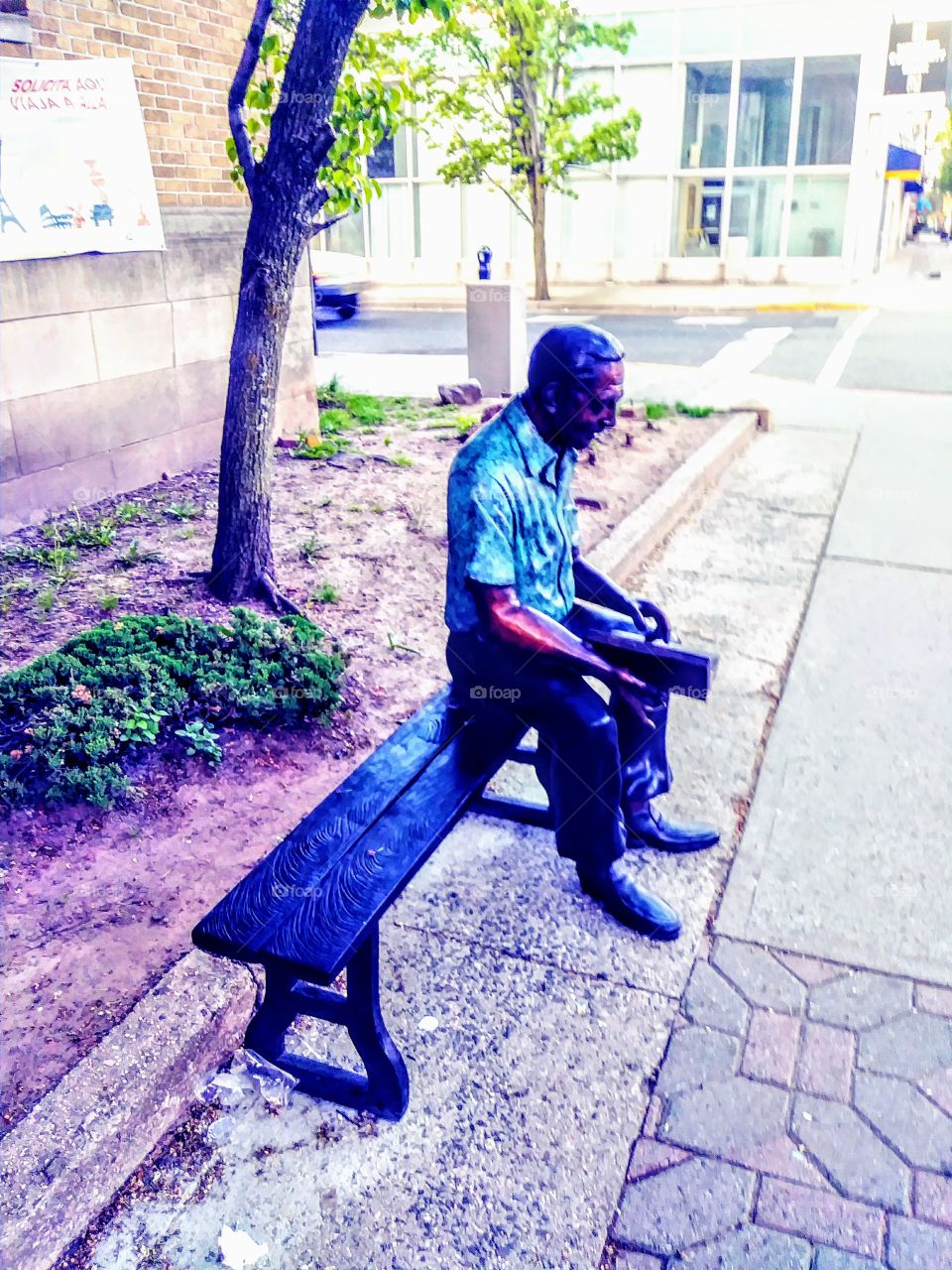 A statue of a man sitting on a bench in Bayonne New Jersey.