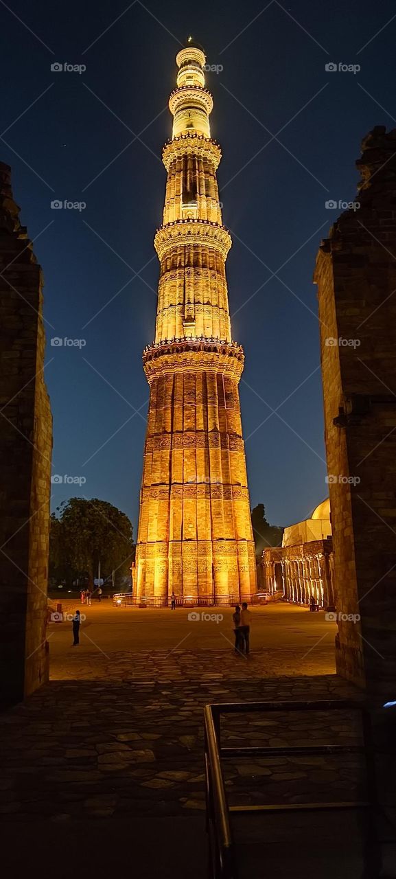 The monument shown is Qutub Minar, a minaret and "victory tower". It is a World Heritage Site in the Mehrauli area of South Delhi, India.