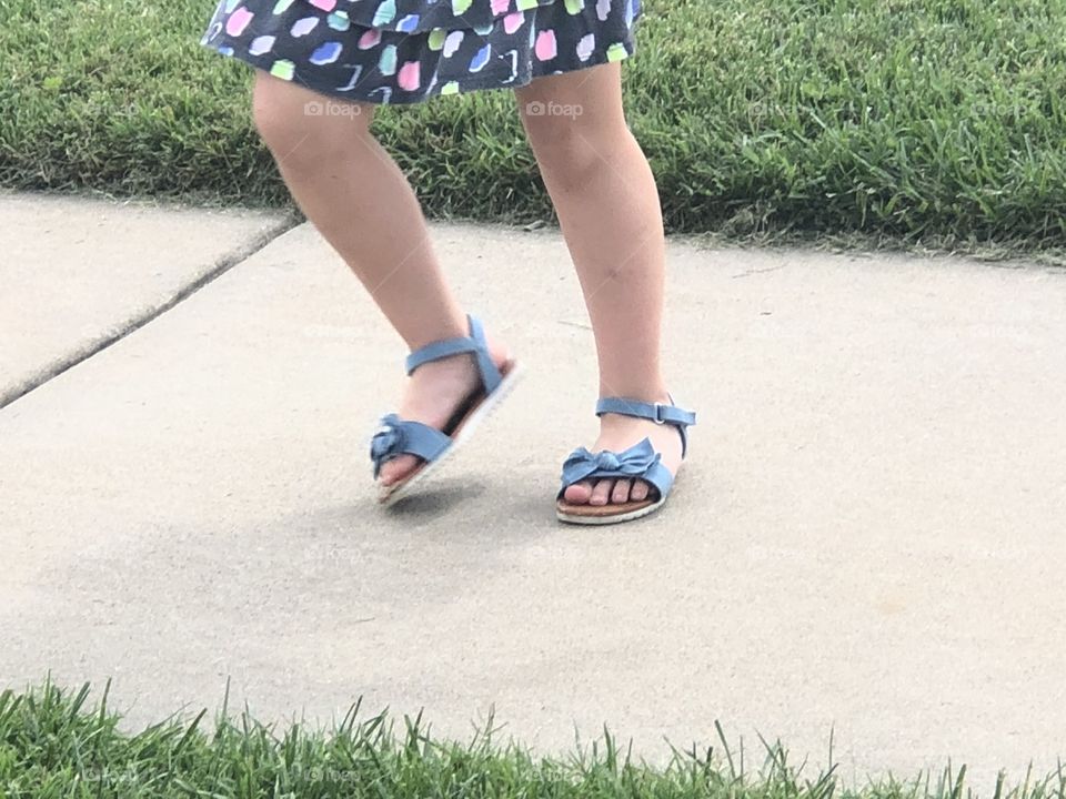 Little girl runs and hears her shoes flop on the cement