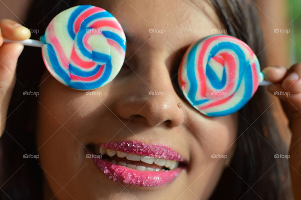 Beautiful woman with sugar coated pink lips,flaunting huge sugary lollipops.