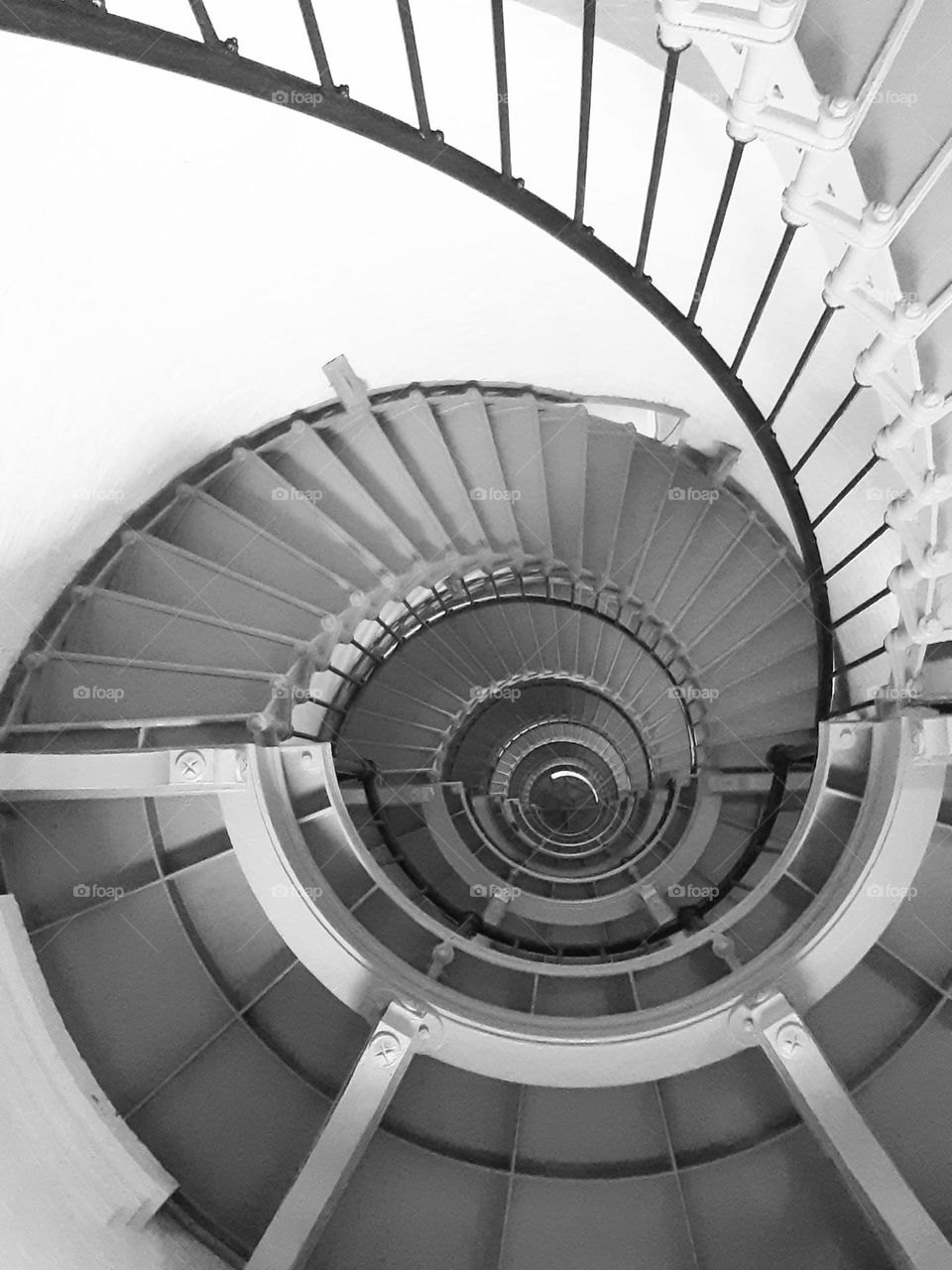 A black and white photo of the steep spiral staircase of the Ponce Inlet Lighthouse.