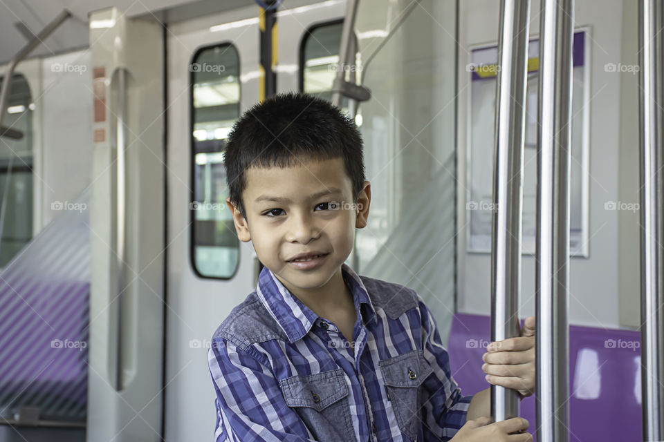 Asian boy holding stainless steel poles in the train.