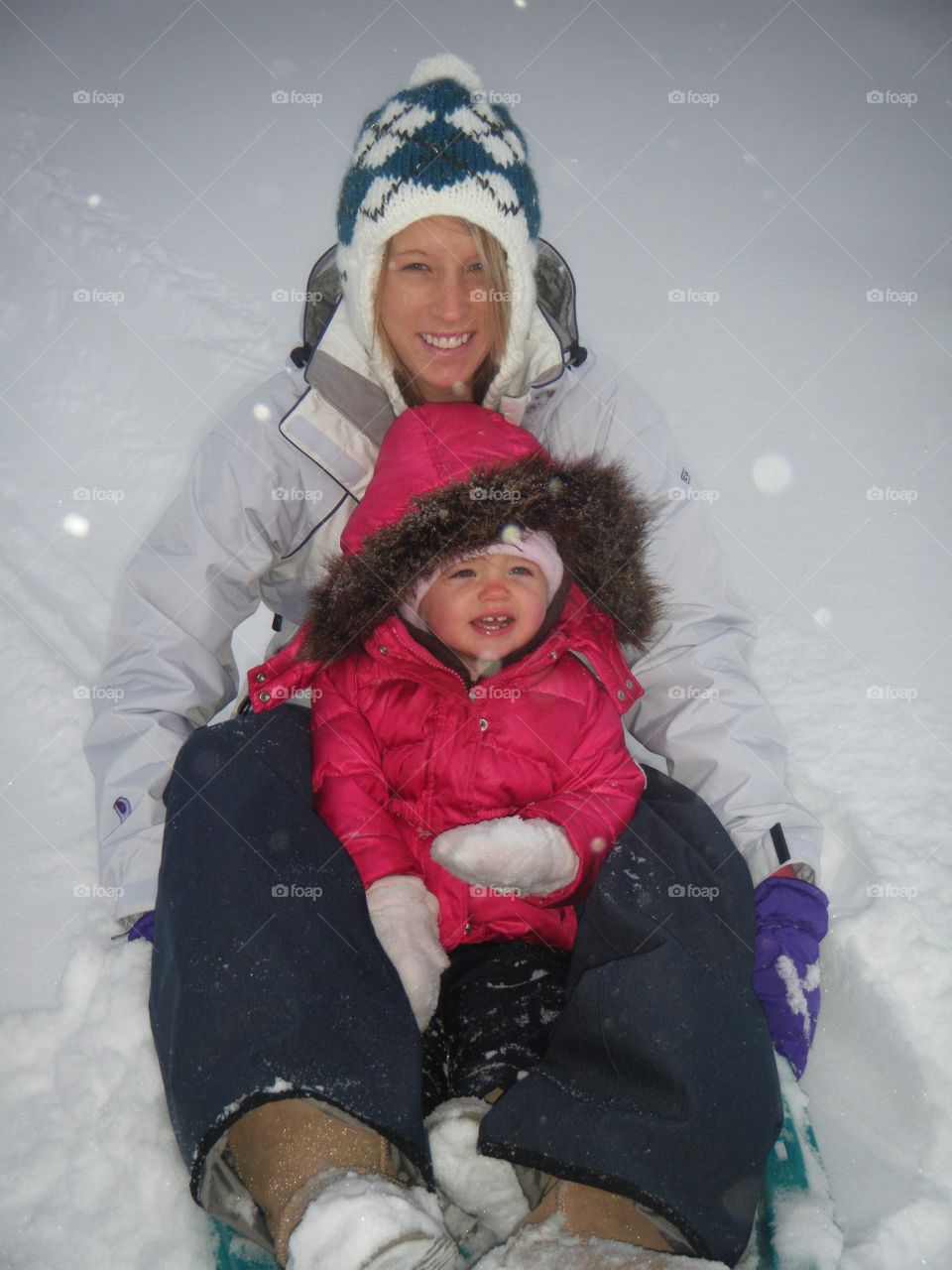 Mama And Her Baby Sledding In The Snowfall 