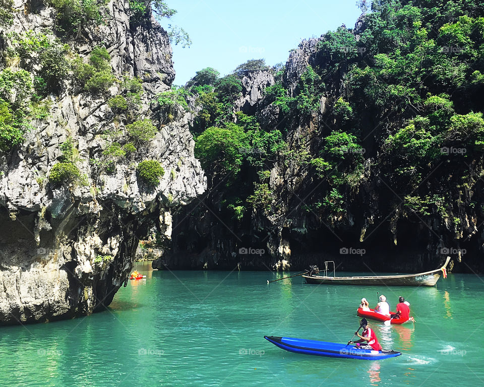 People swimming in boats among the rocks in the blue sea in Thailand 