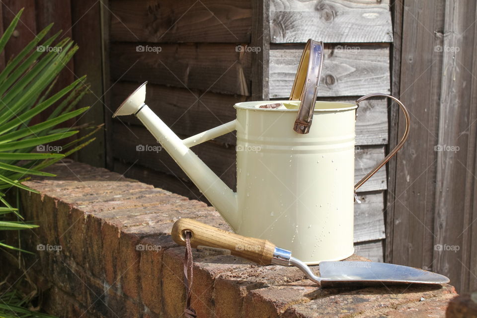 Vintage watering can on a garden wall