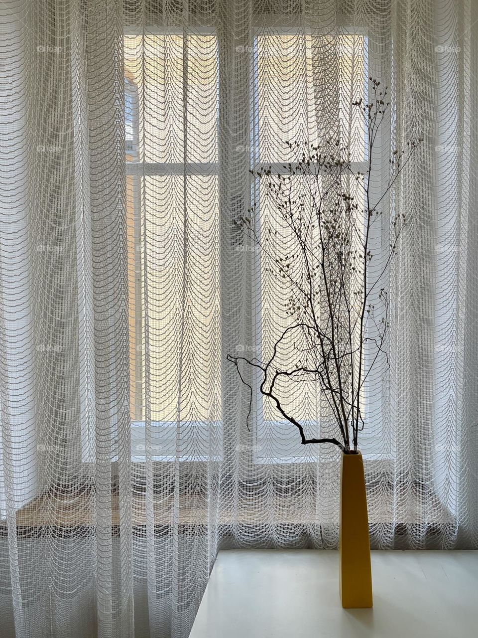 Dry flowers in yellow vase on the window background 