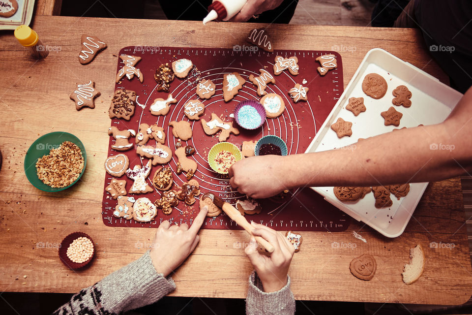 Baking Christmas cookies. Christmas gingerbread cookies in many shapes decorated with colorful frosting, sprinkle, icing, chocolate coating, toppers, put on table. Baking traditional cookies. Family celebrating Christmas. Baking at home