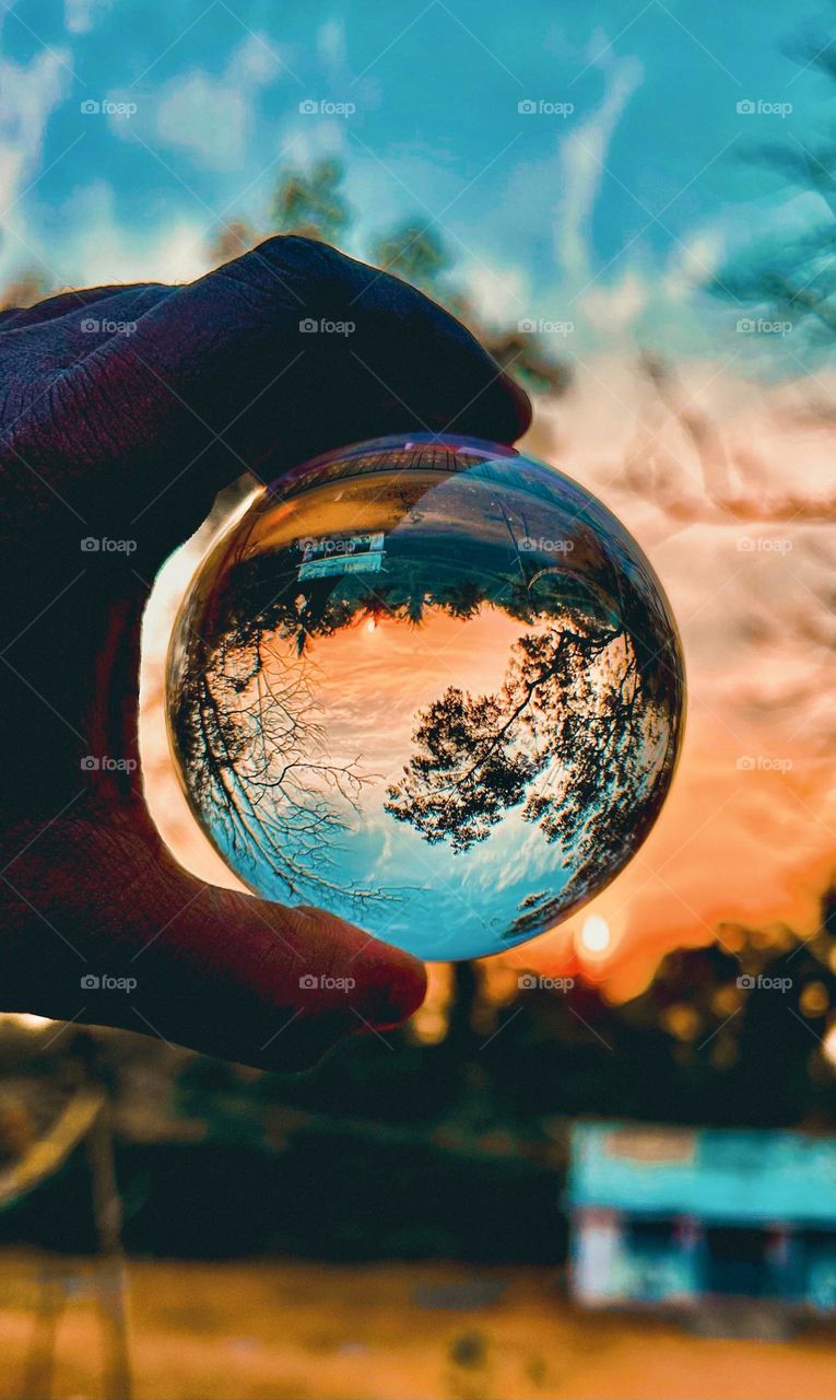 A reflection of sunset sky and sun through the lens ball 