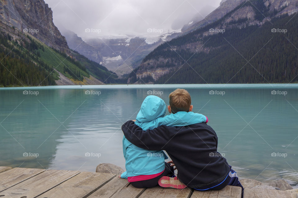 Brother and sister sitting by Lake Louise