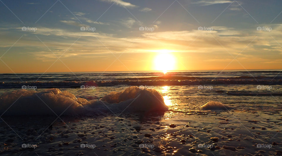 Golden sunset Gulf Of Mexico foamy waves over seashell covered shore