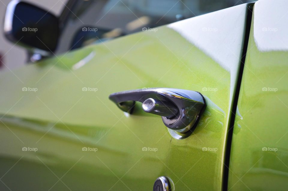 pastel green door from a retro car. on the polished door there is a chrome-plated handle with a button.